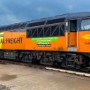 Long side view of Colas class 56 in orange and yellow livery