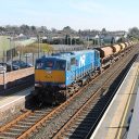 An engineering train hauling ballast trucks passes Antrim station in Northern Ireland seen from an elevated position above the tracks