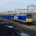 Freight train carrying bulk ballast running alongside a Pendolino on the West Coast Main Line in London