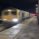 Freight train speeds through a station at night