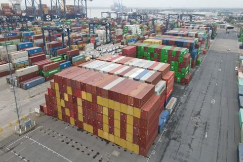 Drong picture of a stack of shipping containers, coloured red and yellow and arranged to say "KC III"