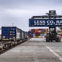 Tesco container with "Less CO2" logo being loaded by reach stacker onto an intermodal train at Granegmouth