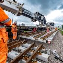 Crane lifts track panel into place while engineer supervises