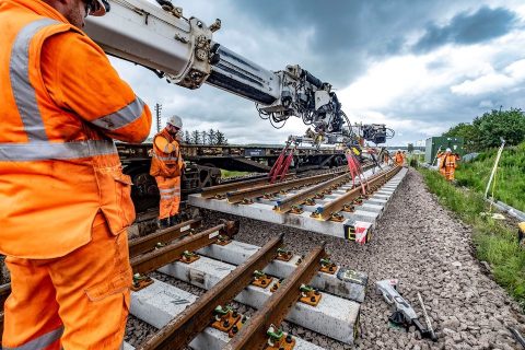 Crane lifts track panel into place while engineer supervises