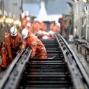 Orange suited engineers work on railway tracks