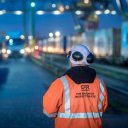 Railway inspector with back to camera looks out over freight terminal